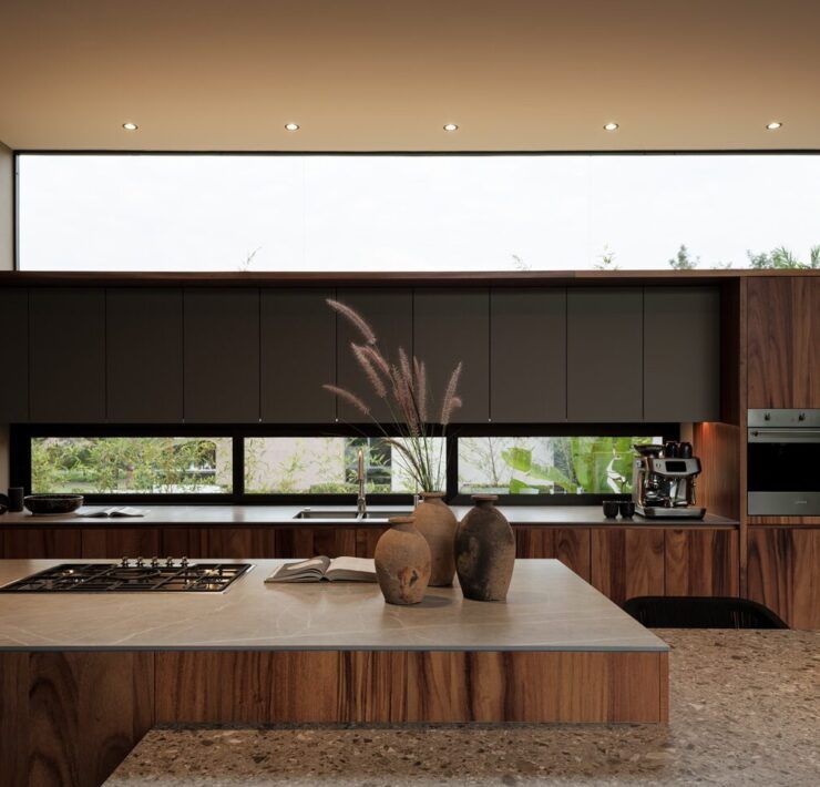Cocina de Casa Kerany con madera, campana e isla de piedra