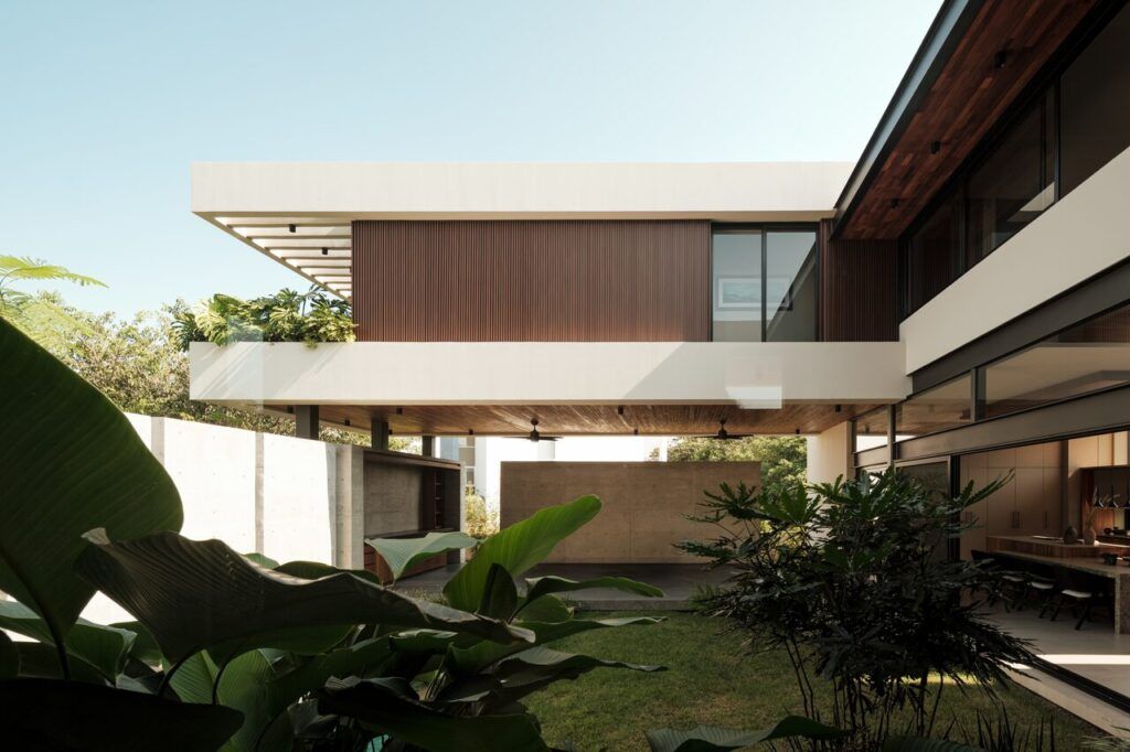 Fachada de Casa Kerany con volúmenes fragmentados, madera y jardín tropical