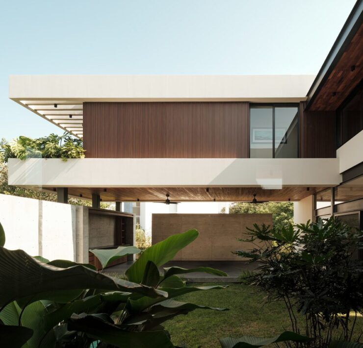 Fachada de Casa Kerany con volúmenes fragmentados, madera y jardín tropical