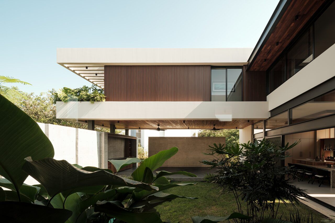 Fachada de Casa Kerany con volúmenes fragmentados, madera y jardín tropical