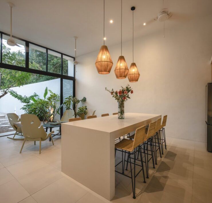 Volumen social a doble altura de Casa Mikelín con cocina y comedor integrados abiertos al jardín