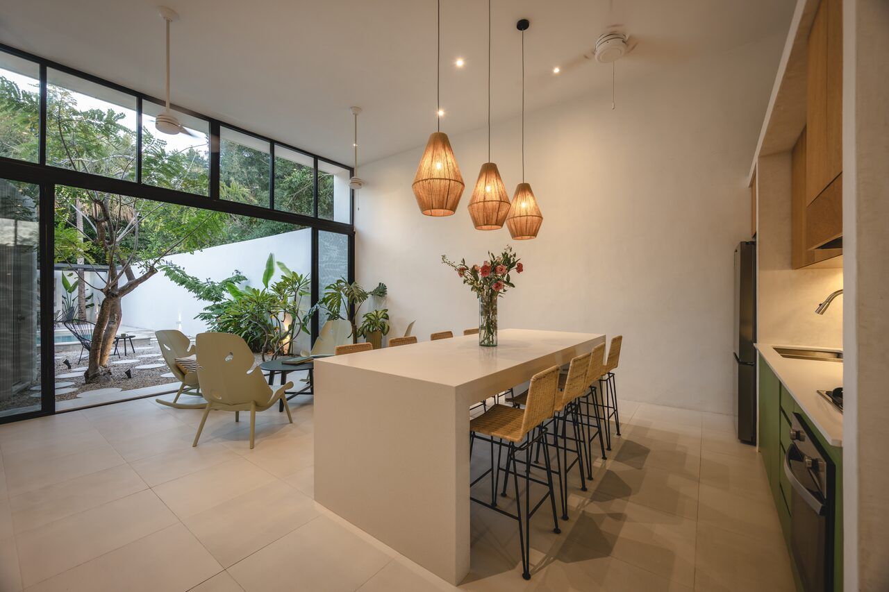Volumen social a doble altura de Casa Mikelín con cocina y comedor integrados abiertos al jardín