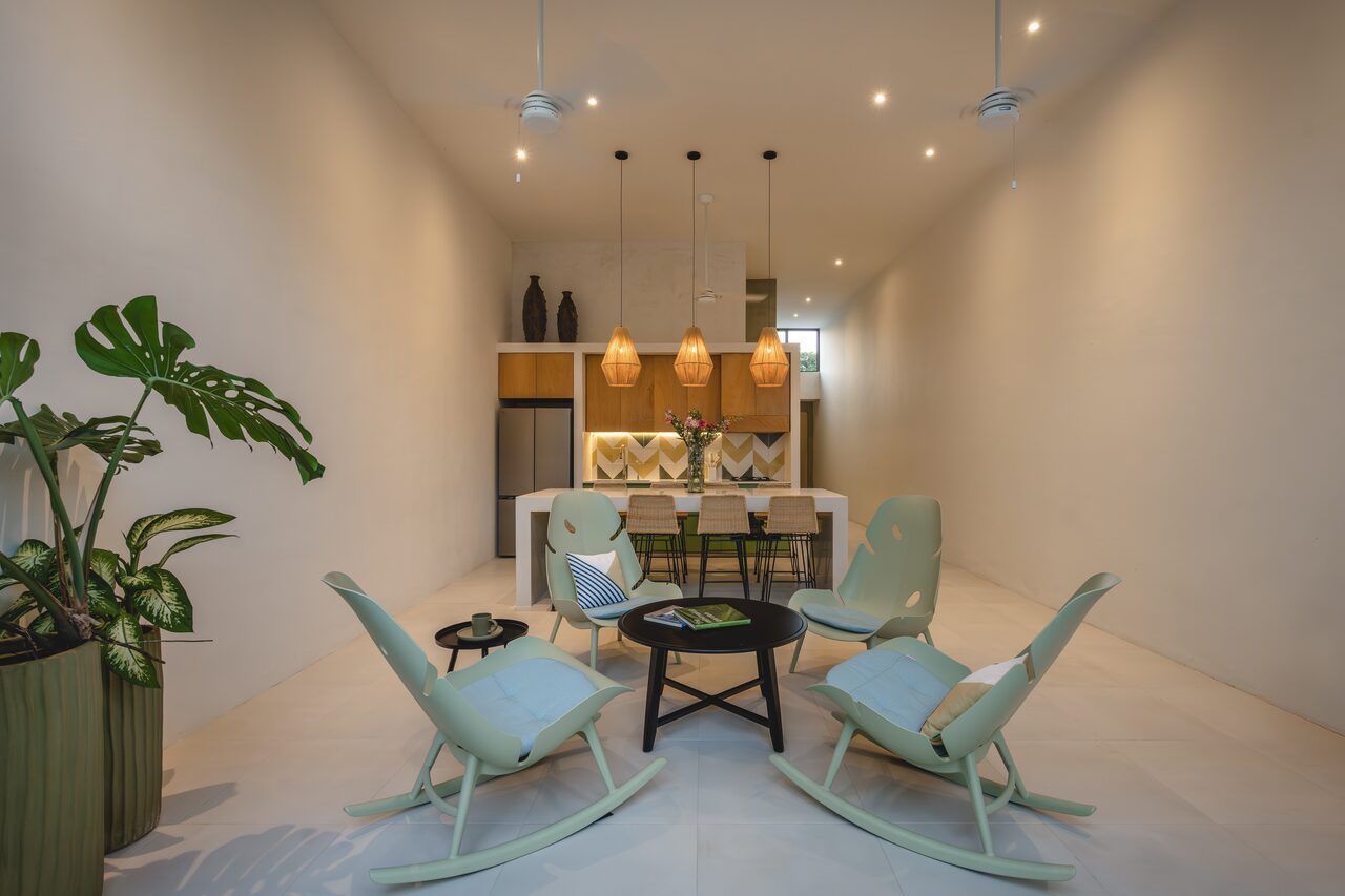 Comedor de Casa Mikelín con sillas y vegetación interior bajo doble altura