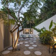 Patio privado de Casa Mikelín con árbol, piso de círculos de concreto e iluminación nocturna