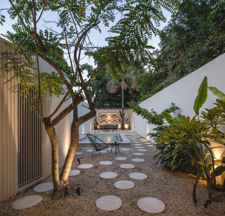 Patio privado de Casa Mikelín con árbol, piso de círculos de concreto e iluminación nocturna