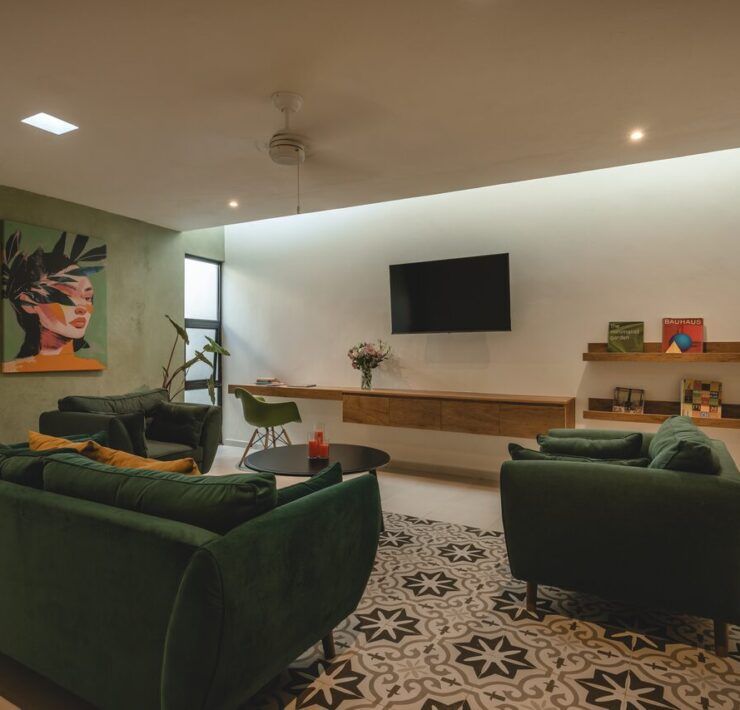 Sala de Casa Mikelín con sofá verde y piso de pasta artesanal