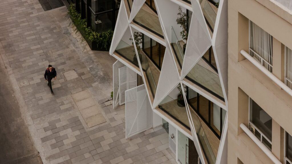 Detalle de la fachada triangular con paneles metálicos perforados de Casa Roma 350