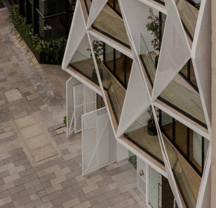 Detalle de la fachada triangular con paneles metálicos perforados de Casa Roma 350