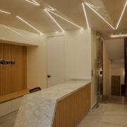 Lobby de Casa Roma 350 con plafones triangulares iluminados y recepción
