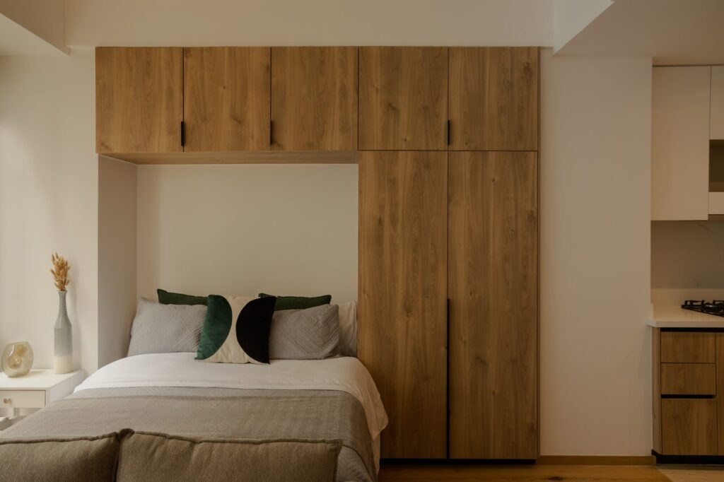 Recámara de un loft de Casa Roma 350 con cabecera de madera y cocina integrada