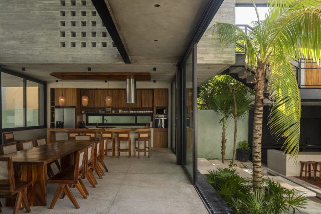 Cocina y comedor de Casa Vihara con madera del sitio y palmeras interiores