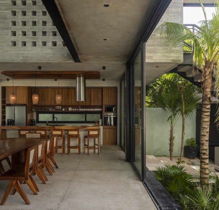 Cocina y comedor de Casa Vihara con madera del sitio y palmeras interiores