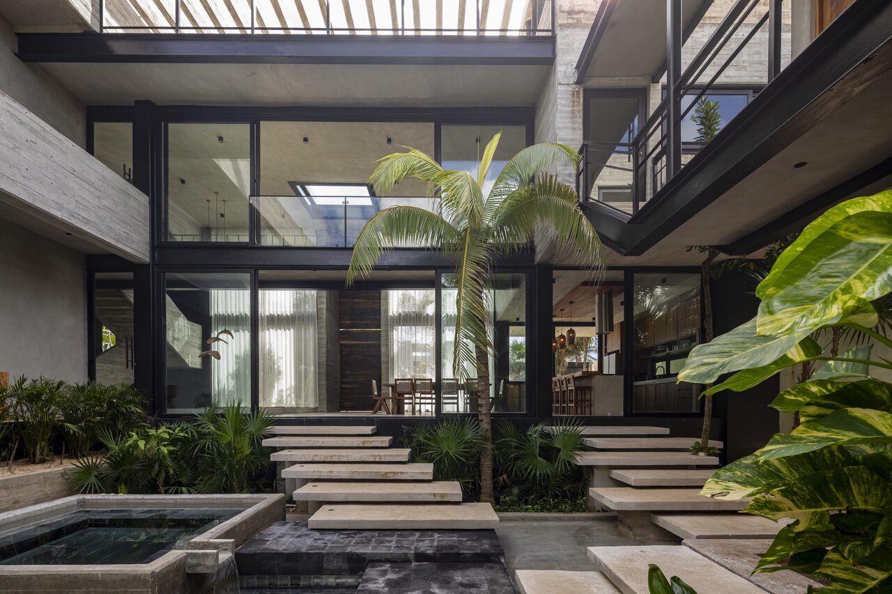 Patio central de Casa Vihara con escalinatas sobre espejo de agua y doble altura