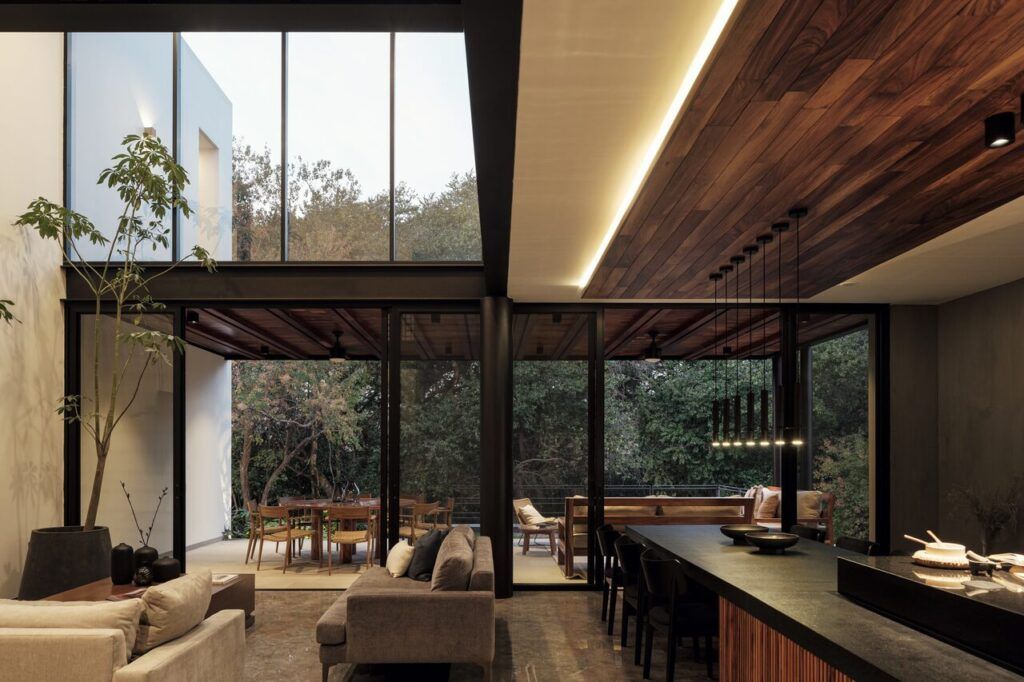 Sala a doble altura de Casa Amadar con ventanales abiertos al jardín