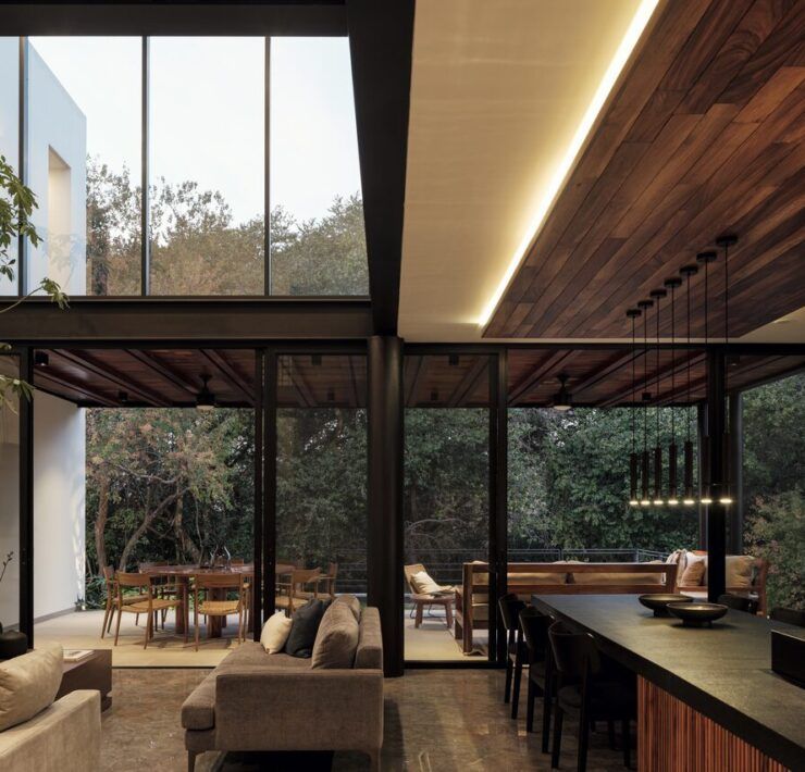 Sala a doble altura de Casa Amadar con ventanales abiertos al jardín