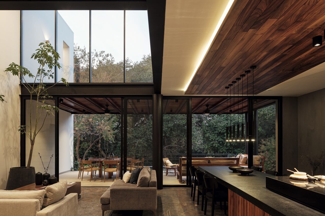 Sala a doble altura de Casa Amadar con ventanales abiertos al jardín