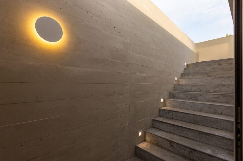 Muro de Casa Martinica con aplique circular iluminado junto a la escalera