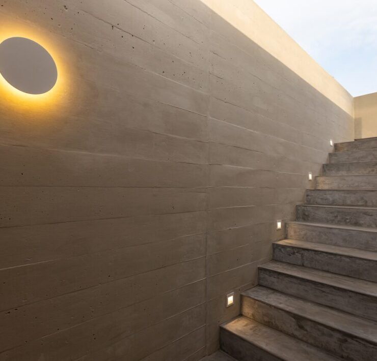 Muro de Casa Martinica con aplique circular iluminado junto a la escalera