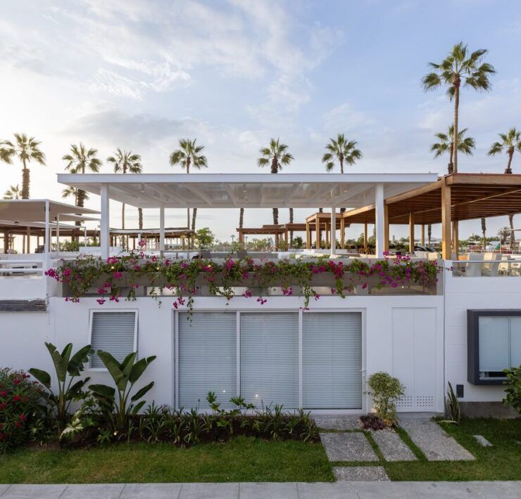 Fachada blanca de Casa Martinica con jardín, bugambilias y palmeras del balneario