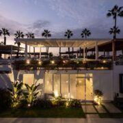 Fachada de Casa Martinica iluminada de noche con jardín