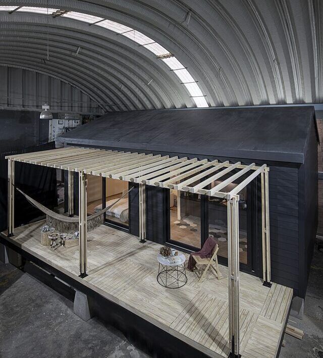 Casa Yoli de noche, tiny house sobre palafito con terraza iluminada