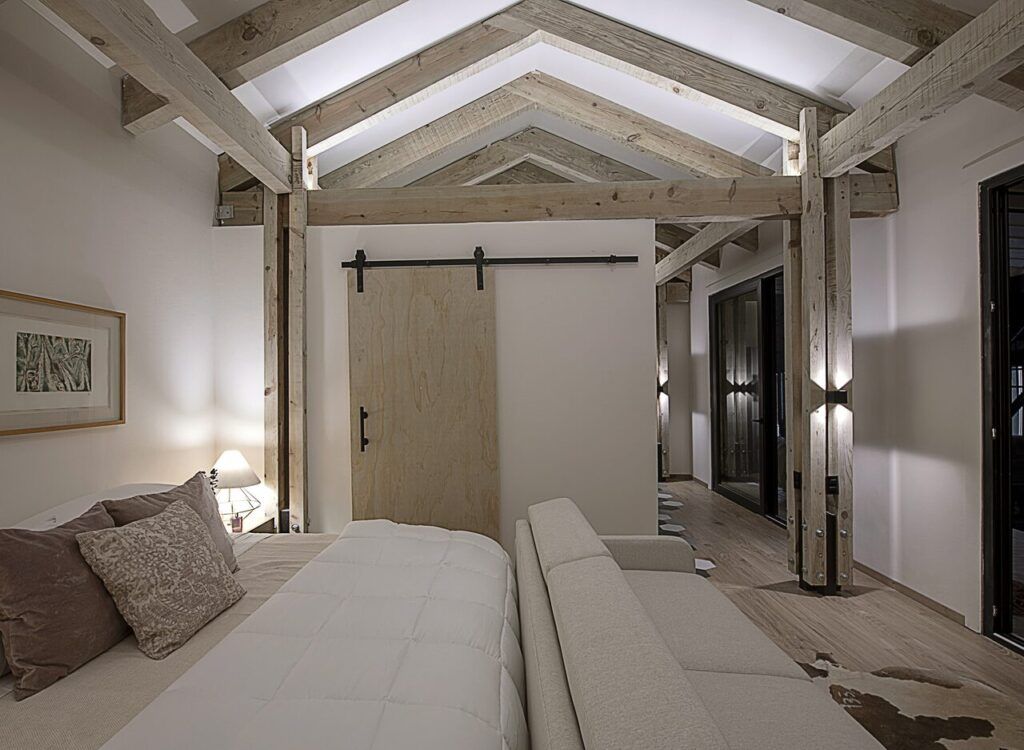 Recámara de Casa Yoli con puerta tipo granero y techo de madera