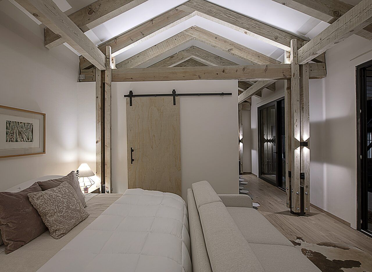 Recámara de Casa Yoli con puerta tipo granero y techo de madera