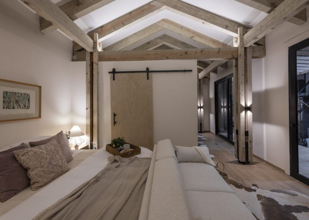 Recámara de Casa Yoli con techo de madera a dos aguas y puerta tipo granero