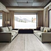Alfombra Frizzantino de G.T.DESIGN en tono gris perla en una sala de chalet con dos sofás y ventanales con vista a la nieve
