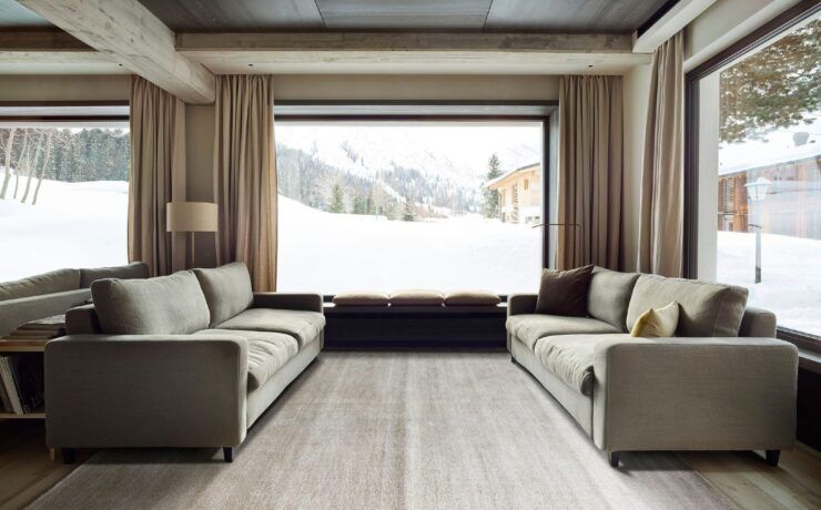 Alfombra Frizzantino de G.T.DESIGN en tono gris perla en una sala de chalet con dos sofás y ventanales con vista a la nieve