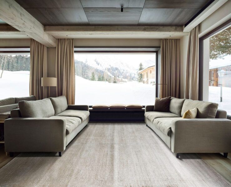 Alfombra Frizzantino de G.T.DESIGN en tono gris perla en una sala de chalet con dos sofás y ventanales con vista a la nieve