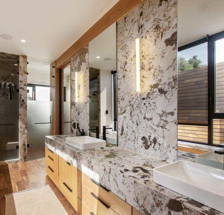 Baño de Casa Ficus con tocador de mármol de vetas oscuras y madera