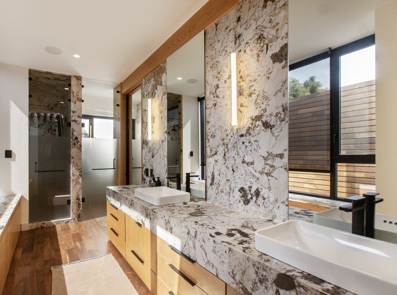 Baño de Casa Ficus con tocador de mármol de vetas oscuras y madera