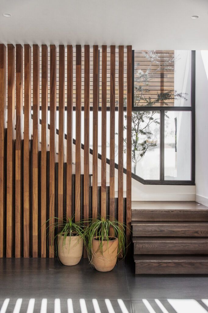 interiorismo cálido en Puebla con esta escalera de Casa Ficus con celosía de listones de madera y macetas de barro