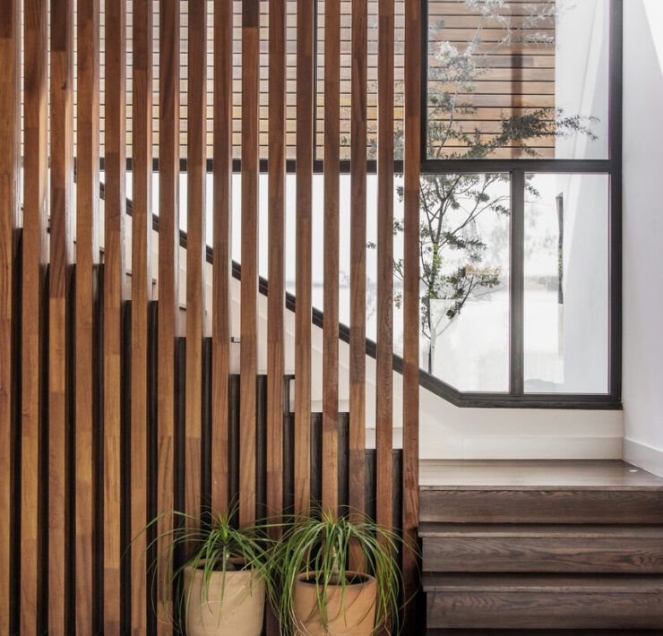 Escalera de Casa Ficus con celosía de listones de madera y macetas de barro