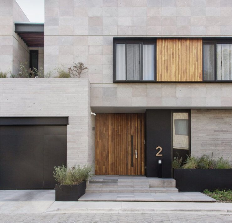 Fachada de Casa Ficus en Puebla con cantera, puerta de madera y vegetación