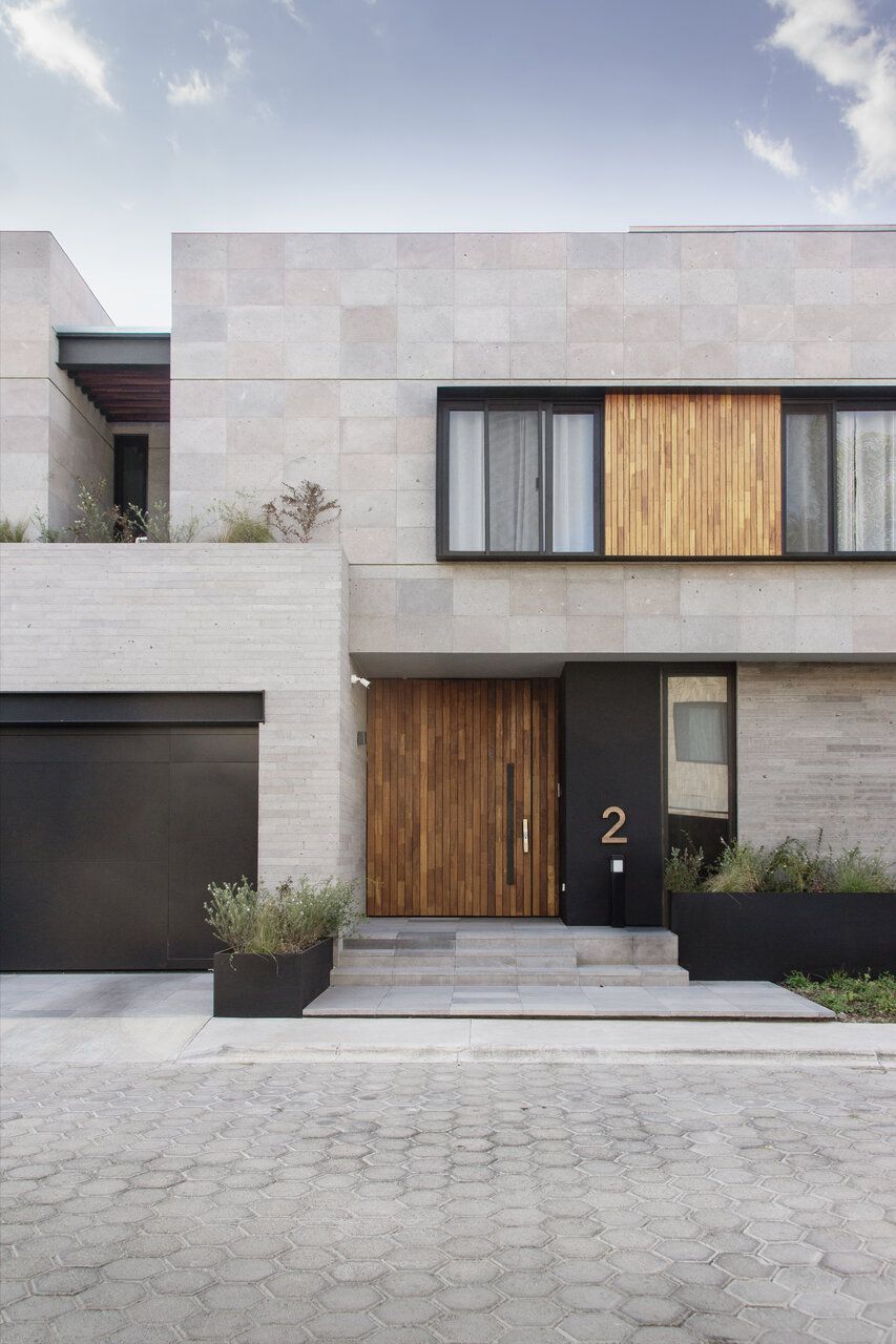 Fachada de Casa Ficus en Puebla con cantera, puerta de madera y vegetación
