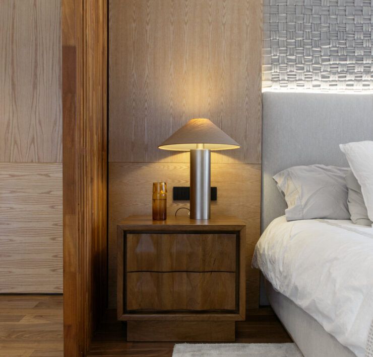 Recámara principal de Casa Ficus con buró de madera y lámpara de luz cálida