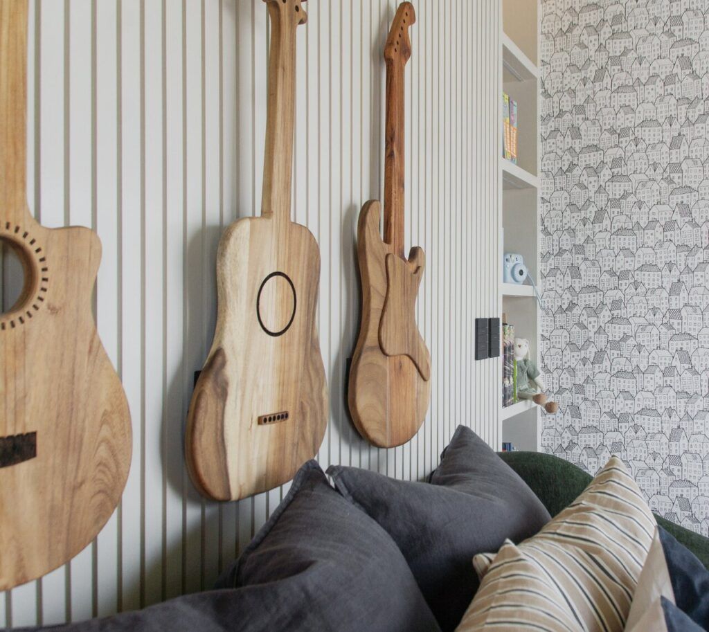 sala de Casa Ficus con guitarras de madera como decoración en el muro un interiorismo cálido en Puebla