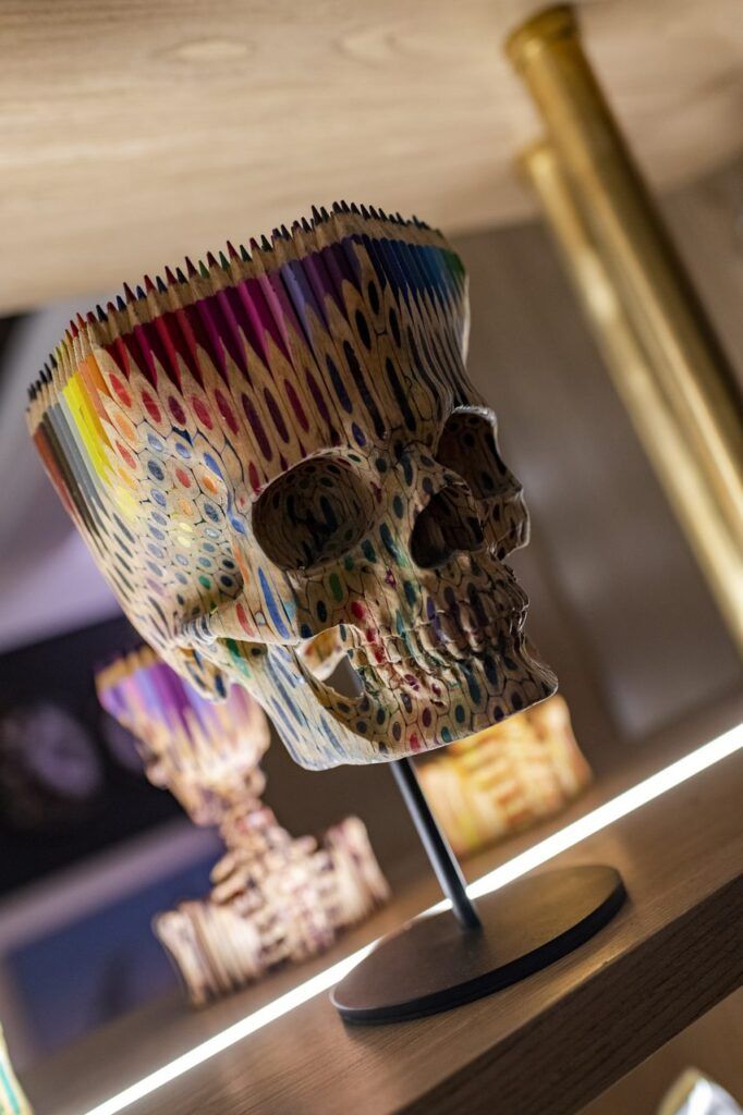 Escultura de calavera hecha con lápices de colores sobre una repisa iluminada de Casa Mineral