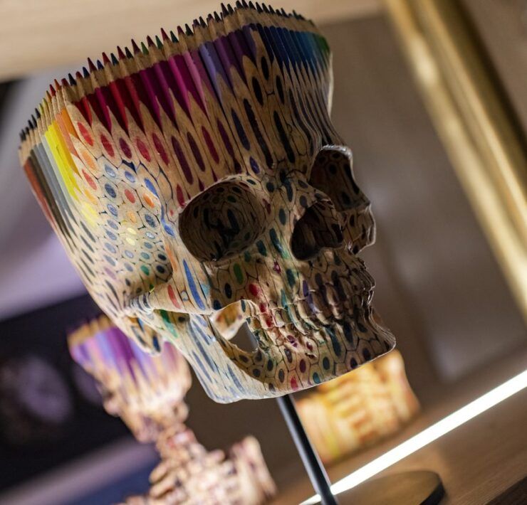 Escultura de calavera hecha con lápices de colores sobre una repisa iluminada de Casa Mineral