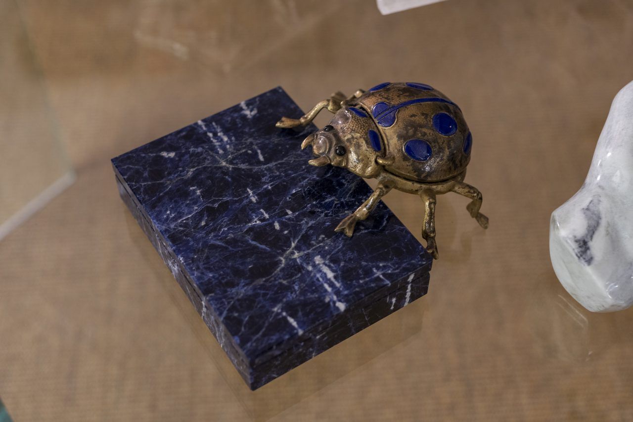 Escarabajo de bronce con incrustaciones azules sobre caja de piedra azul veteada en Casa Mineral