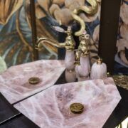 Lavabos de cuarzo rosa con grifería dorada y manerales de cuarzo en el baño de visitas de Casa Mineral