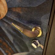 Manija de puerta dorada con textura de piel de serpiente y punta de cascabel en Casa Mineral