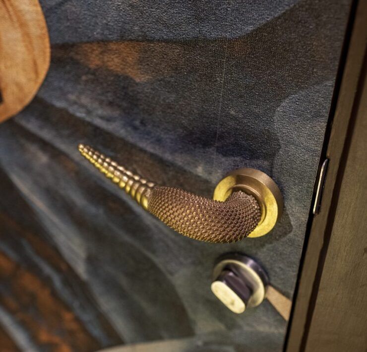 Manija de puerta dorada con textura de piel de serpiente y punta de cascabel en Casa Mineral