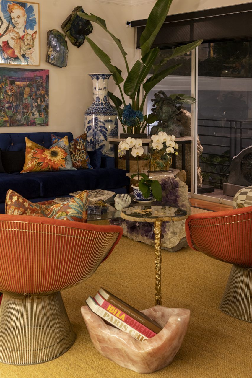 Rincón de la sala de Casa Mineral con cuenco de cuarzo rosa como revistero, sillones rojos y jarrón de porcelana azul y blanca