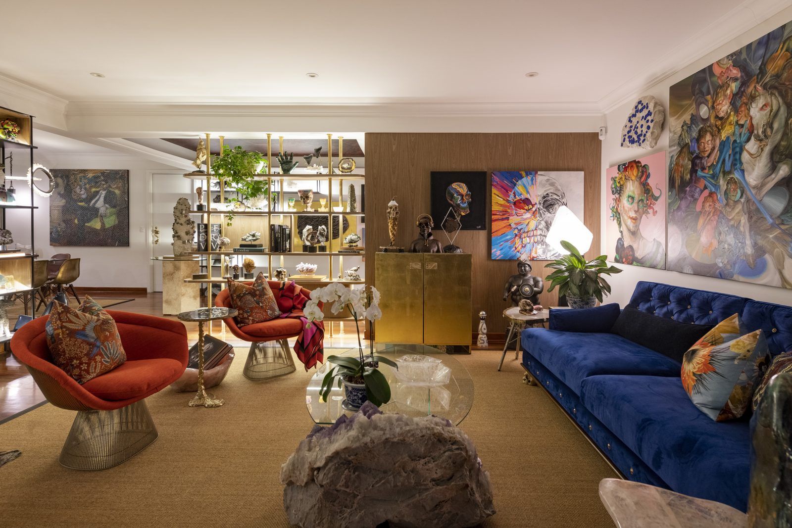 Sala de Casa Mineral en San Isidro, Lima, con sillones rojos estilo Warren Platner, sofá azul y mesa de centro de amatista