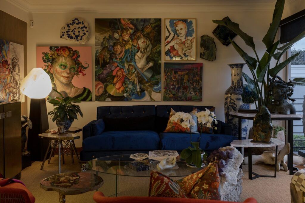 diseño de interiores en Lima de Sala de Casa Mineral con sofá capitonado azul, muro de obras de arte, lámpara de cuarzo y minerales