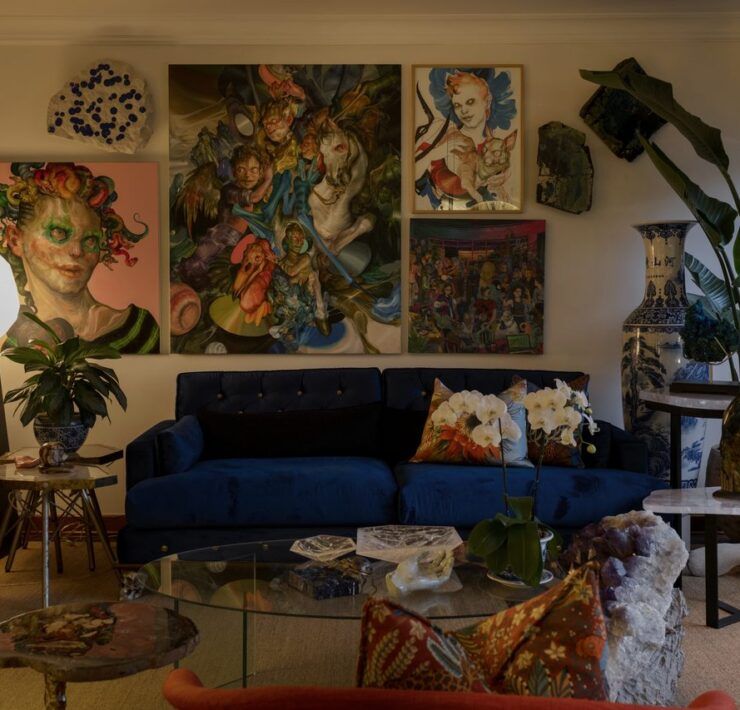 Sala de Casa Mineral con sofá capitonado azul, muro de obras de arte, lámpara de cuarzo y minerales