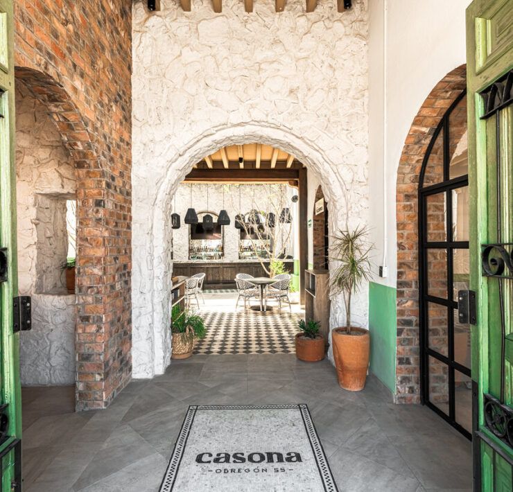 Pasillo con arcos de piedra en Casona Obregón 55, con vista hacia el bar del fondo